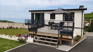 En toetagers bygning med balkon, udendørs siddepladser og havudsigt.