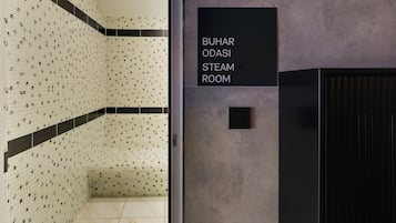 Un baño de vapor con pared de azulejos y un cartel con su nombre.