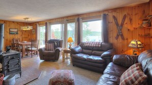 A cozy cabin interior with a dining area, leather sofas, and a fireplace.