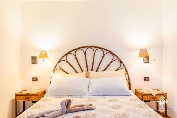 A bed with a unique headboard, two bedside lamps, and a bedside table with a tray. - Almanzar - Seaside residences (Lampedusa)