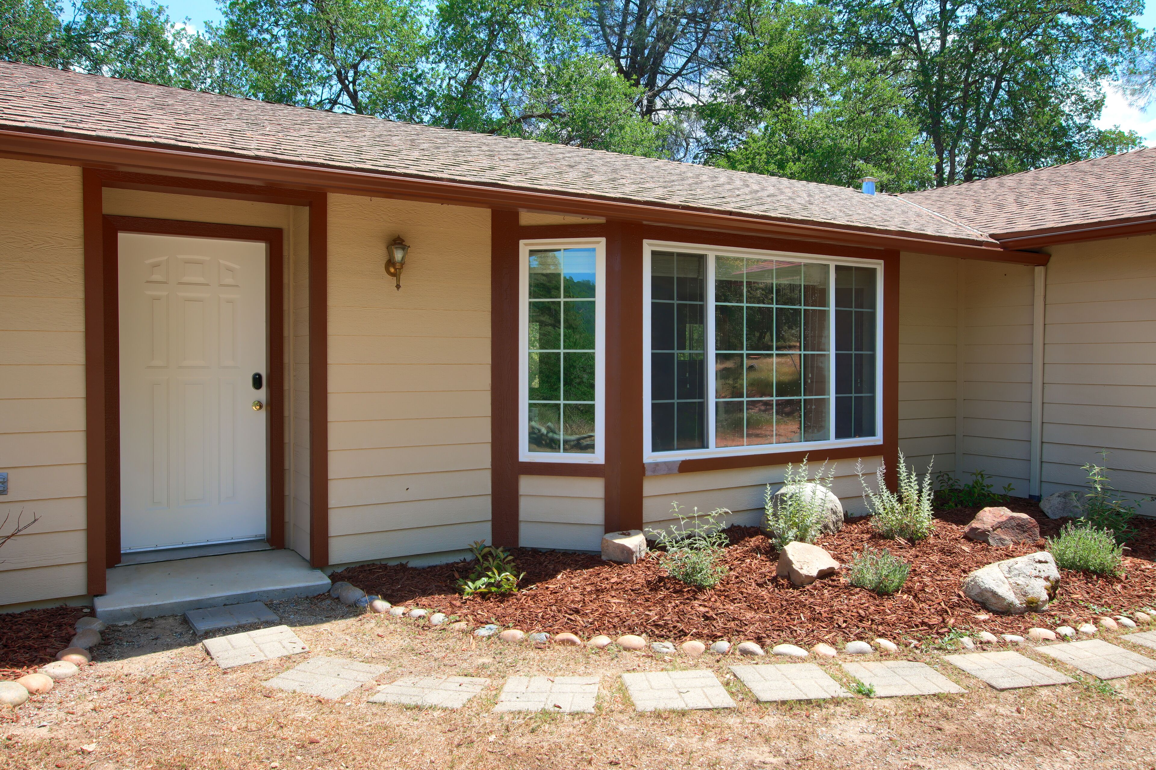 A single-story house with a front door, a large window, and a small porch area.