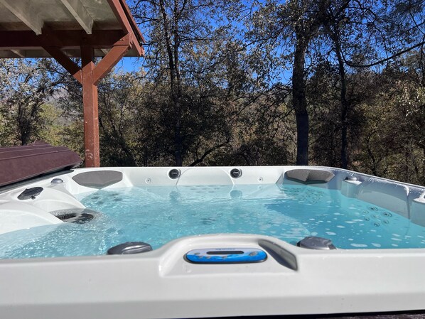 Relax in the outdoor hot tub surrounded by a serene natural setting.