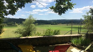 A stone wall with two folding chairs facing a rural landscape with fields and trees. - À la CLAIREFONTAINE (Montignac)