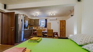 A compact bedroom with a green bedspread, a wooden wardrobe, a kitchen area with a refrigerator, oven, and microwave, and a dining table with chairs. - A2-apartment 50m From the Beach With the sea View (Korcula)