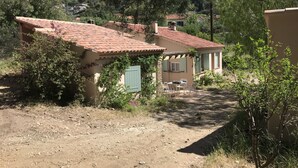 A rustic building with a tiled roof, a small patio with outdoor seating, and a dirt path leading to it. - Bord de Plage (Le Lavandou)