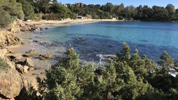 Paisaje costero con aguas azules cristalinas, costa rocosa y abundante vegetación.