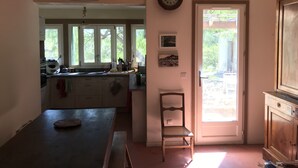 Una cocina con un ventanal amplio, una mesa de comedor, una silla y una puerta que da al exterior.