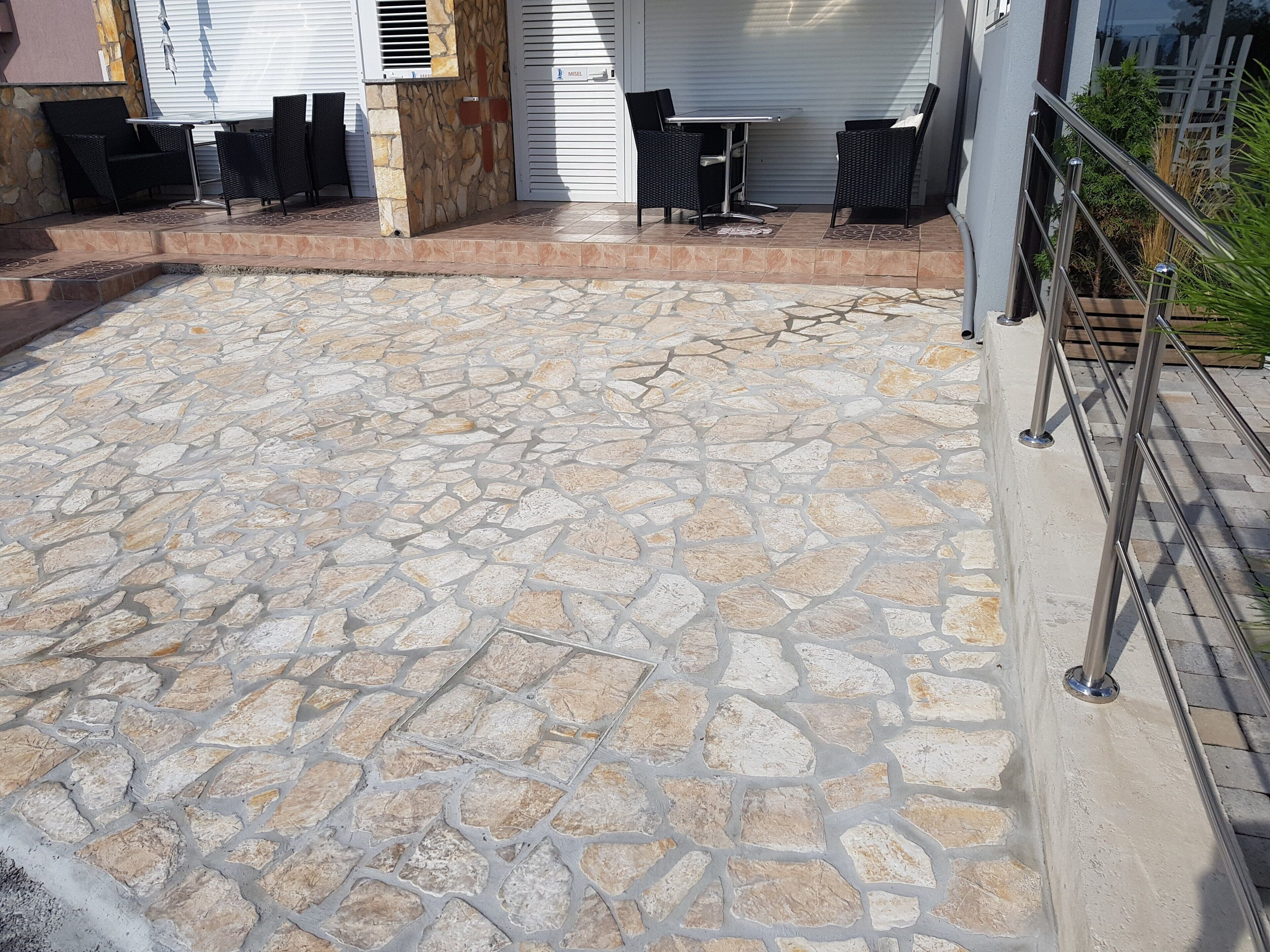 Un patio de piedra con muebles de exterior y barandilla metálica.