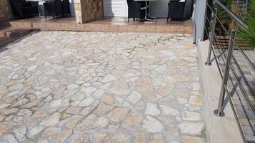 Un patio de piedra con muebles de exterior y barandilla metálica.