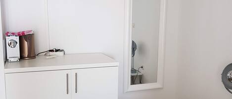 Una habitación de hotel con una cama, un escritorio, un espejo, un televisor y un guardarropa.