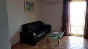 Ein Wohnzimmer mit einer schwarzen Ledersofa, einem Glastisch und einem Fliesenboden.