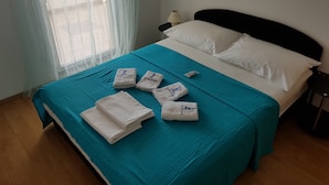 Ein ordentlich bezogenes Bett mit einem türkisfarbenen Bettüberwurf, weißen Kissen und gefalteten Handtüchern.