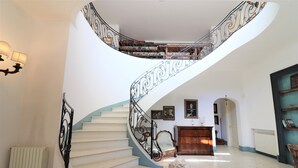 A grand staircase with ornate metal railings, a white radiator, and a wooden chair in a spacious room with a tiled floor. - B b Relais Delle Rose Lecce Iris - Comfort Double (Lecce)