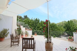 A covered outdoor seating area with a table and chairs, surrounded by potted plants and flowers. - B b Relais Delle Rose Lecce Iris - Comfort Double (Lecce)
