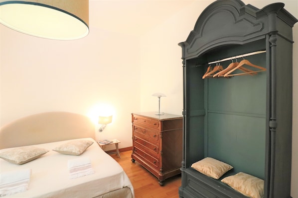 A bedroom with a bed, a dresser, a wardrobe, and a nightstand.