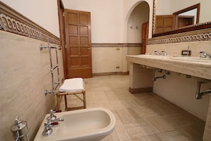 A bathroom with a bathtub, a sink with two faucets, and a wooden door.