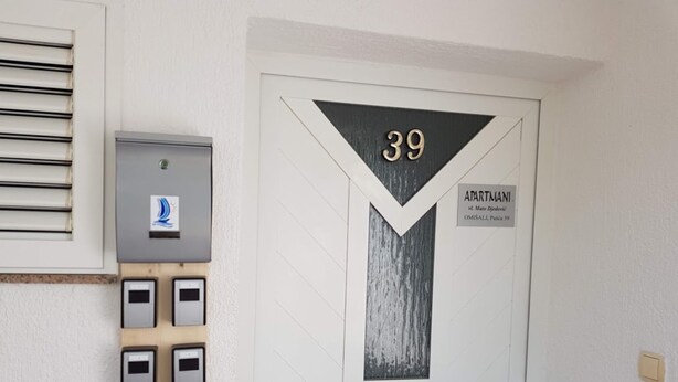 Een witte deur met het nummer 39, een bord dat het een appartement aangeeft, en een codeklissysteem.