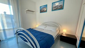 Ein Schlafzimmer mit einem Bett, einem Fenster und zwei Bildern an der Wand.