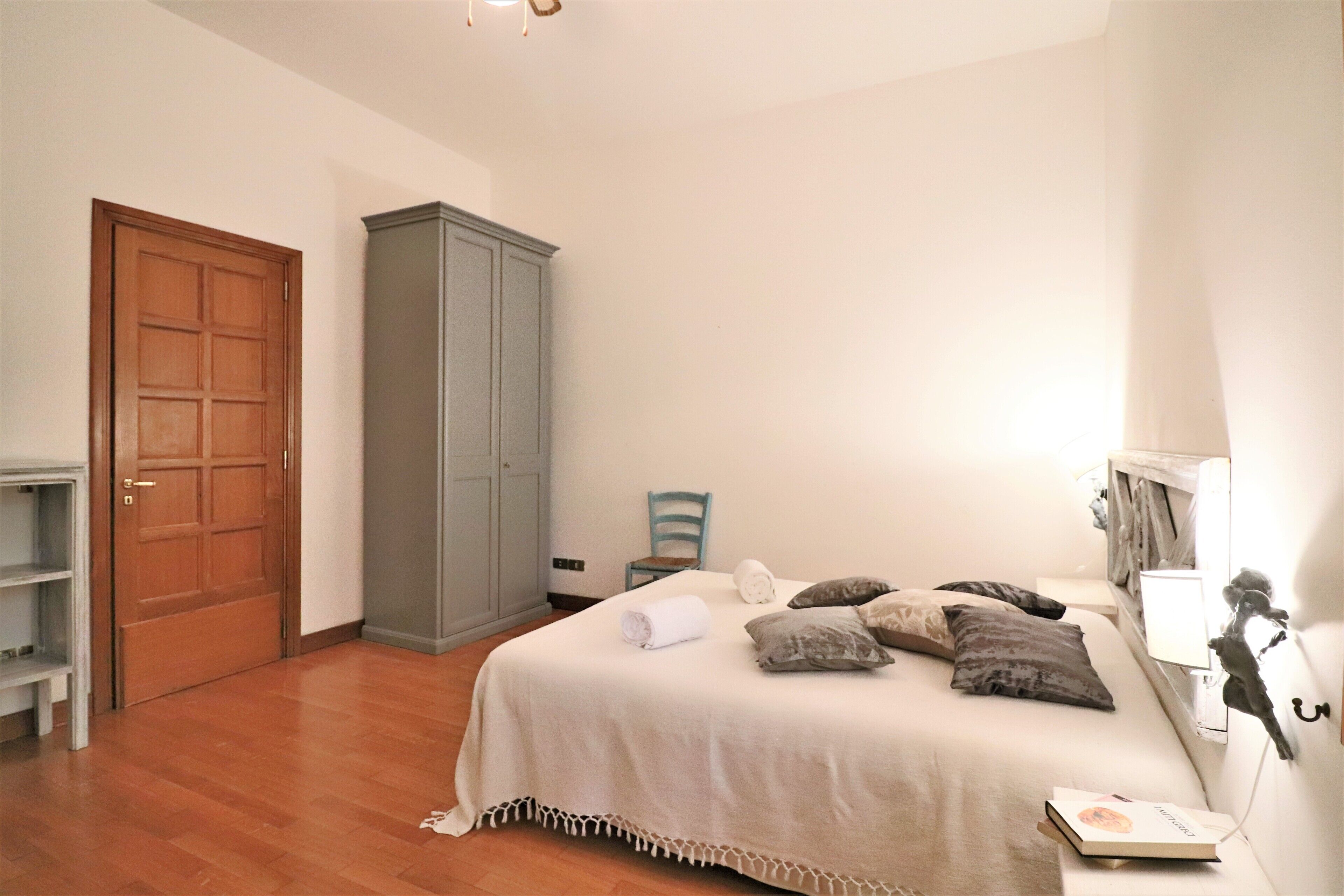 A bedroom with a bed, a wardrobe, a chair, and a desk.