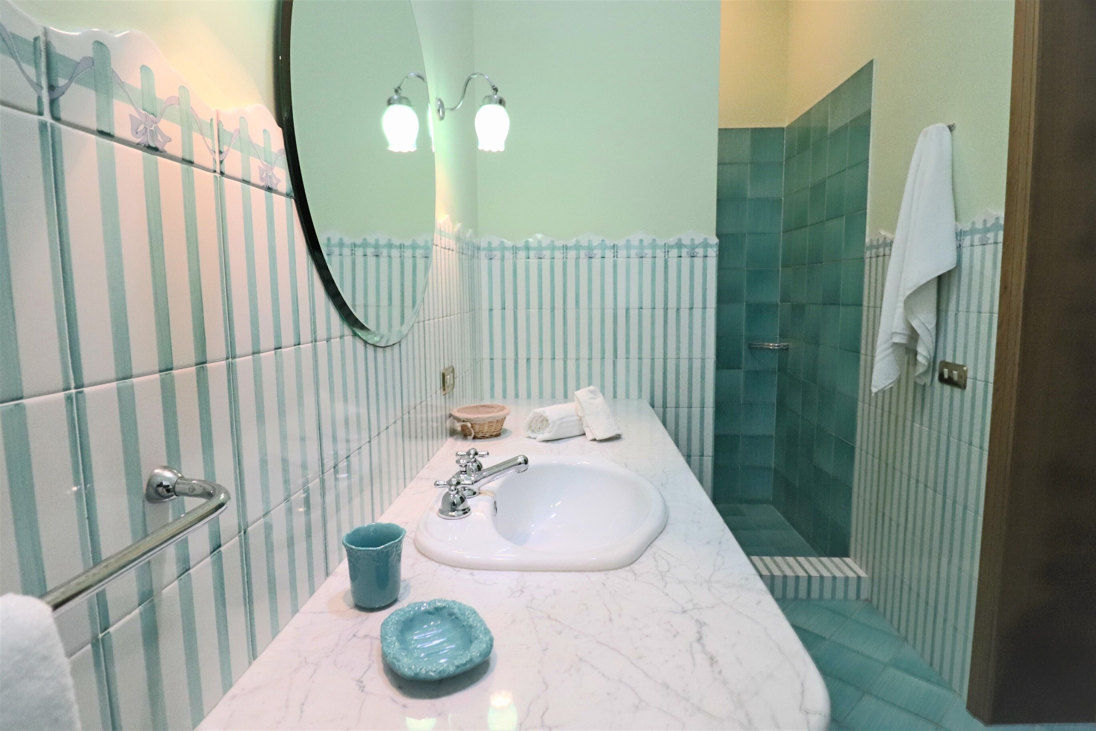 Une salle de bain avec un lavabo blanc, un miroir et un espace douche.