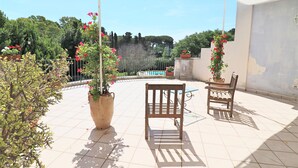 Une terrasse avec deux chaises en bois, une table et des plantes en pot.