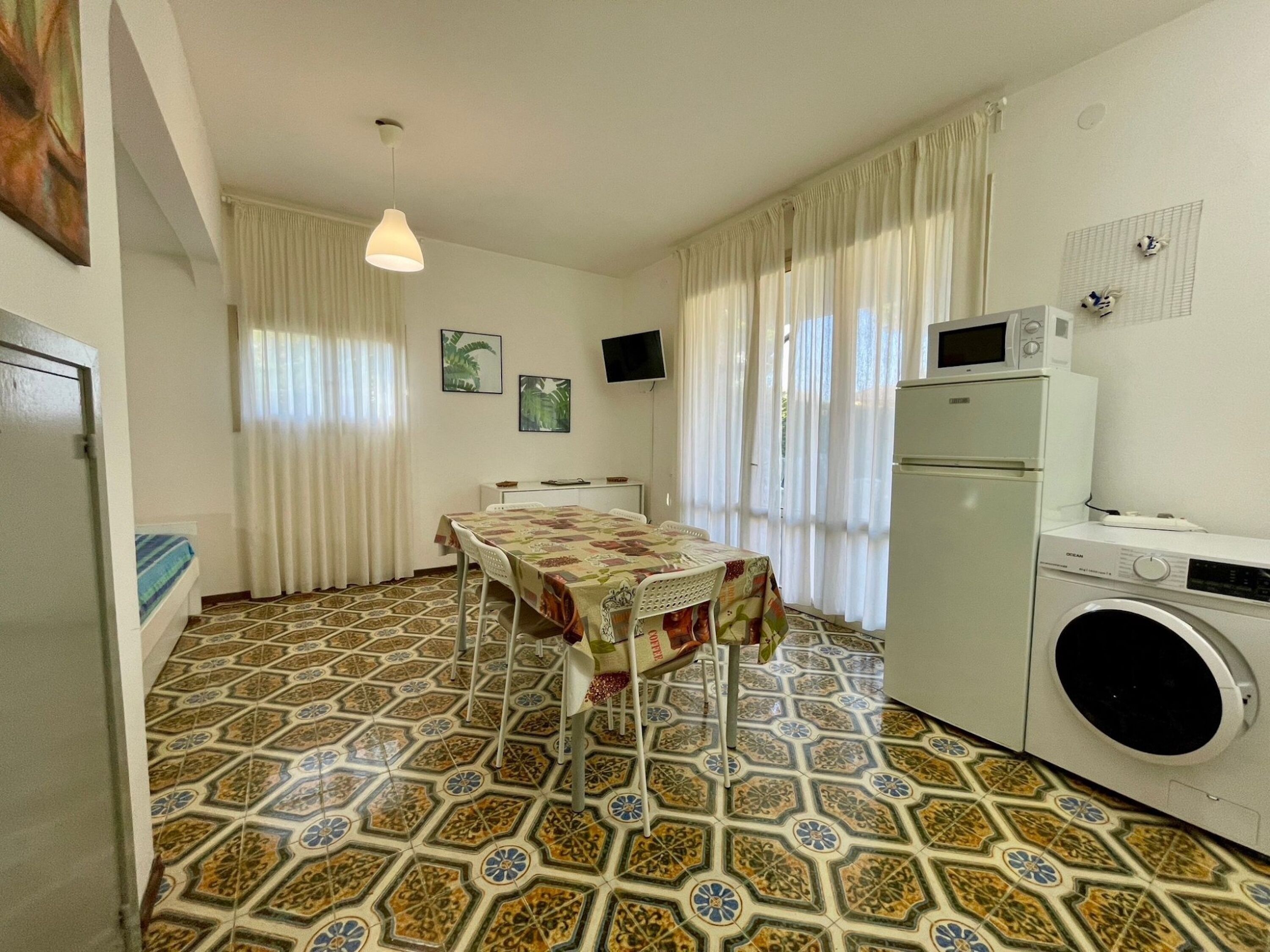 A compact kitchen with a dining table, a washing machine, and a microwave.