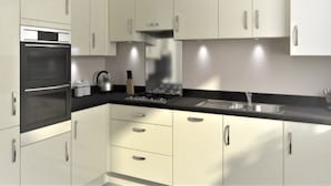 Una cocina moderna con armarios blancos, encimera negra, electrodomésticos de acero inoxidable y una cocina a gas.