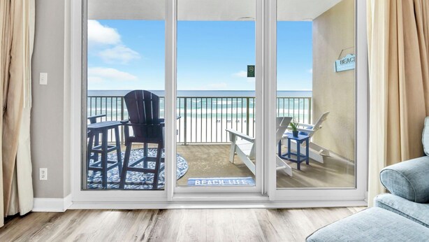 Ein Zimmer mit einer Schiebetür zu einem Balkon mit Blick auf den Strand.