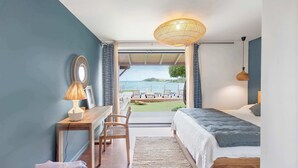 A bedroom with a bed, desk, chair, and a view of the sea. - Villa Baltazar – Waterfront Luxury Villa Facing Pinel Islet, Saint Martin (Cul-de-Sac)