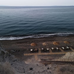 On the beach, black sand, sun-loungers, beach umbrellas