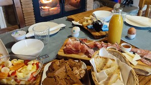 Un bufé de desayuno con diversos alimentos y una estufa de leña al fondo.