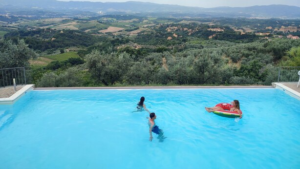 Una piscina infinita con vistas a colinas ondulantes y montañas lejanas.
