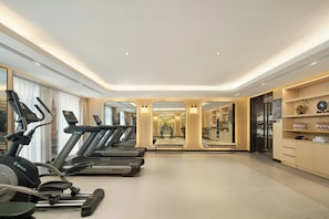 A modern gym with treadmills, exercise bikes, and a mirrored wall.