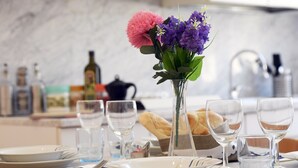 Ett matbord dukat med tallrikar, glas och en vas med blommor.