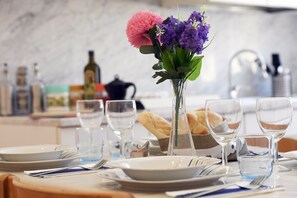 A dining table set with plates, glasses, and a vase with flowers. - Big House Colosseum (Roma)