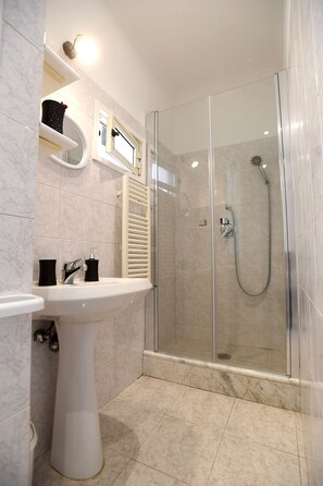 A modern bathroom with a glass-enclosed shower, a pedestal sink, and a towel rack. - Big House Colosseum (Roma)