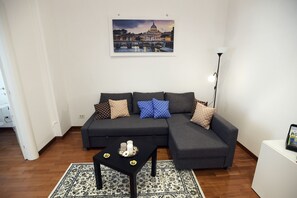 A modern living room with a sectional sofa, a coffee table, and a framed cityscape painting on the wall. - Big House Colosseum (Roma)