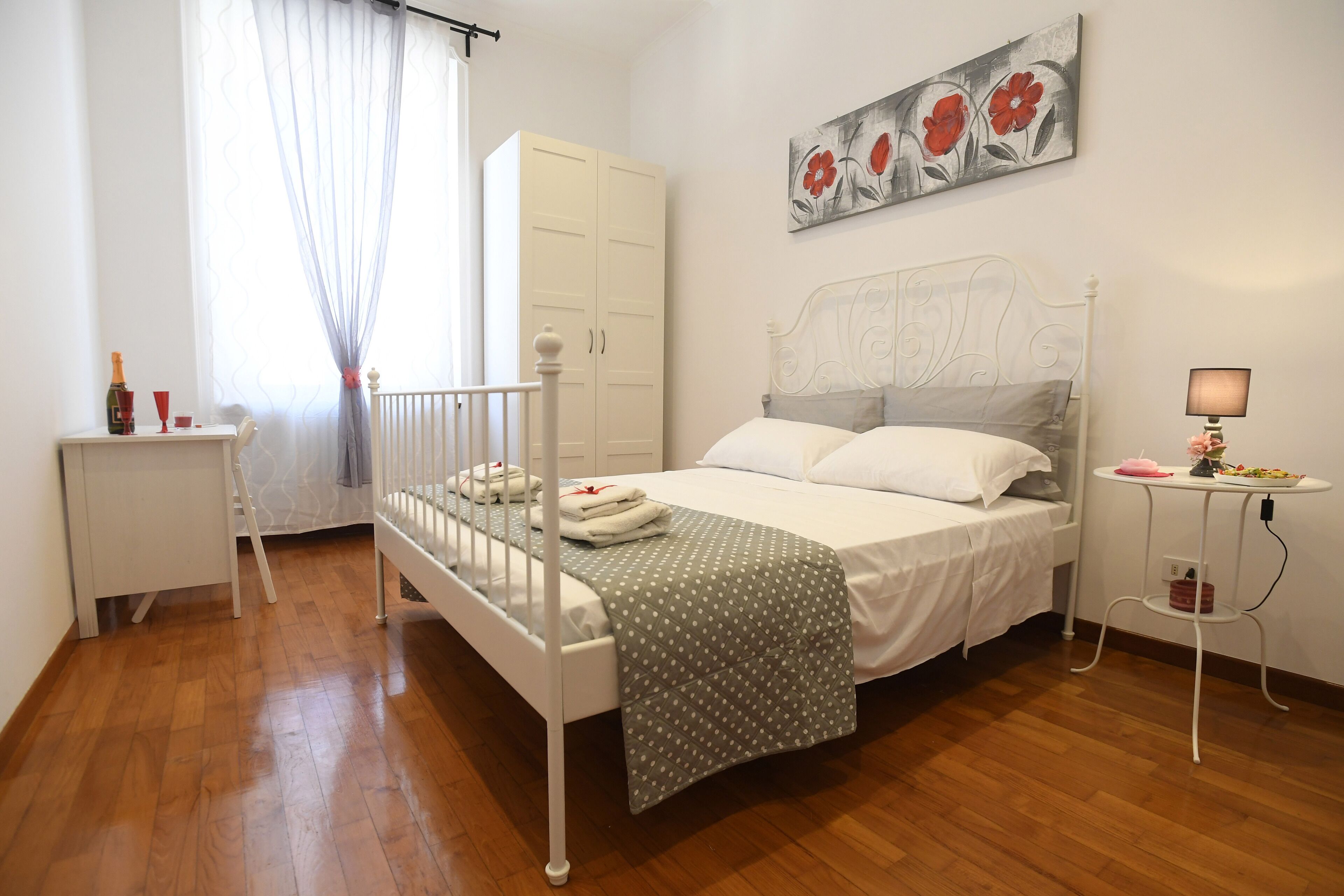 A bedroom with a bed, a wardrobe, a bedside table, and a window with curtains.