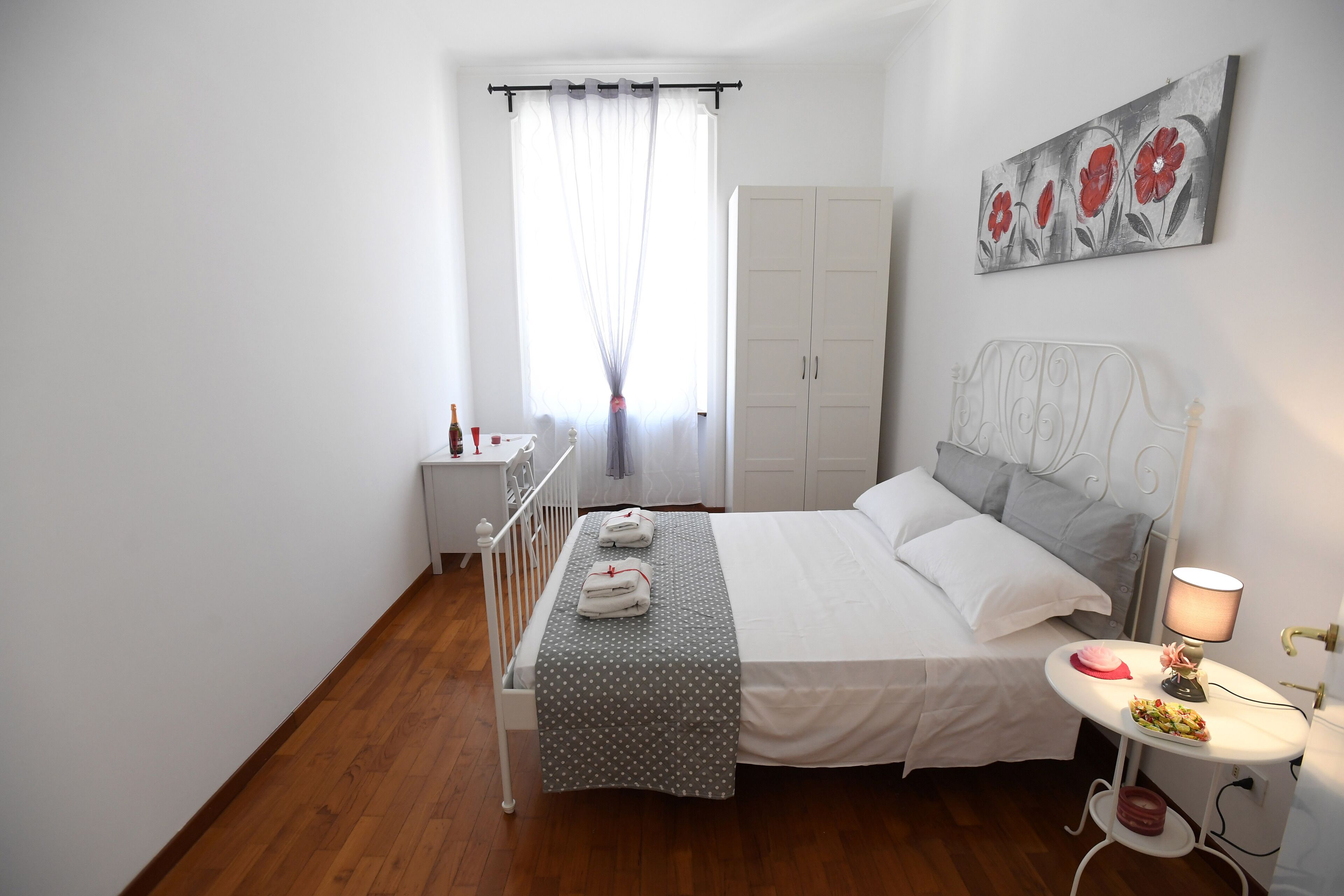 A neatly arranged bedroom with a bed, bedside table, and a painting on the wall.
