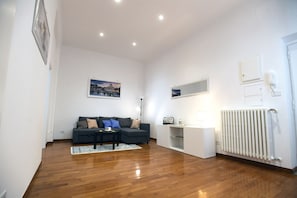 A modern living room with a dark-colored sofa, a small coffee table, and a white cabinet. - Big House Colosseum (Roma)