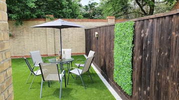 A patio with a table and chairs, surrounded by a brick wall and a wooden fence.