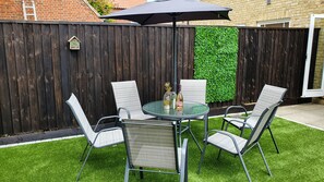 Enjoy al fresco dining on the patio, surrounded by lush greenery and shaded by a stylish umbrella.
