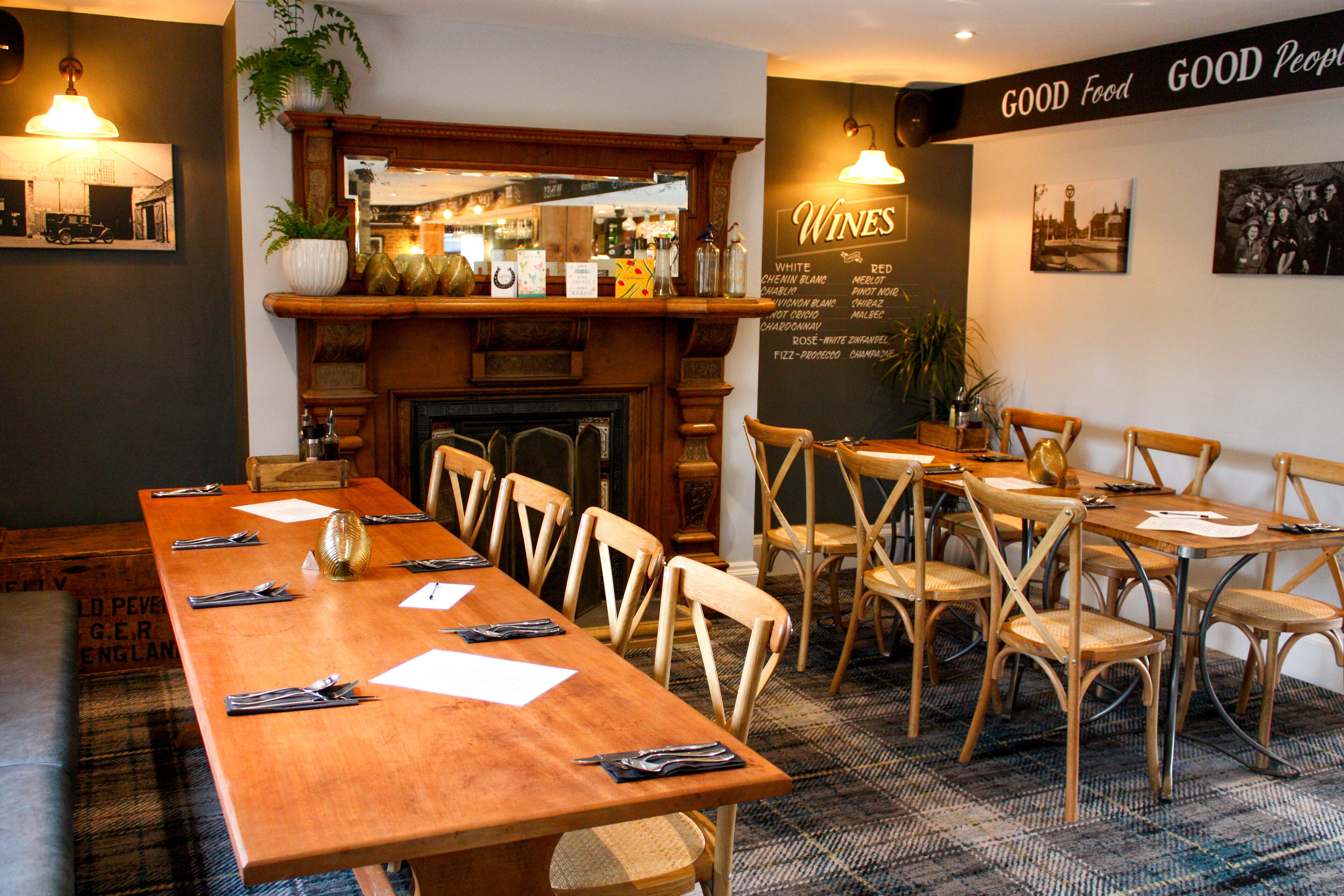 Un restaurant avec une longue table en bois, plusieurs chaises et un tableau affichant le menu au mur.