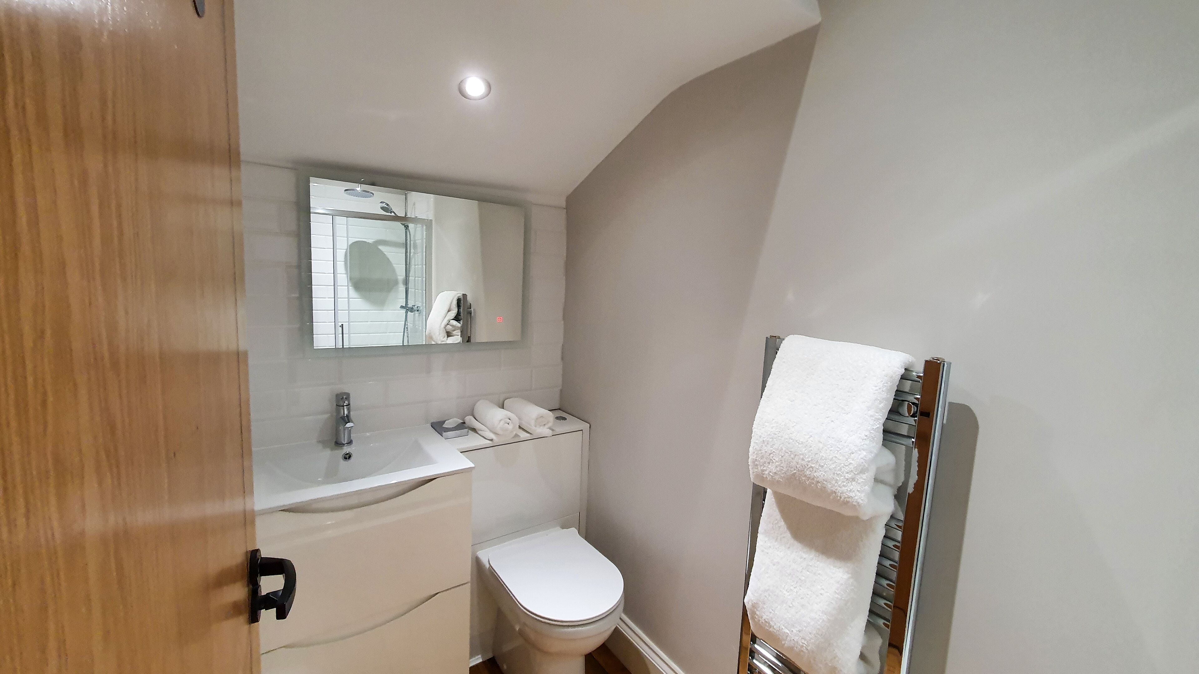 Een badkamer met toilet, wastafel, spiegel en handdoekhouder.