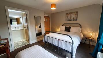A hotel room with a bed, bedside table, lamp, and a painting on the wall.