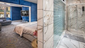 Une chambre moderne avec un grand lit, un téléviseur et une douche à l’italienne.