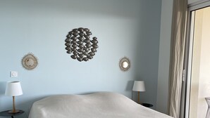 Ein Schlafzimmer mit einem Bett, zwei Nachttischen mit Lampen, einem Deckenventilator und Wanddekoration.