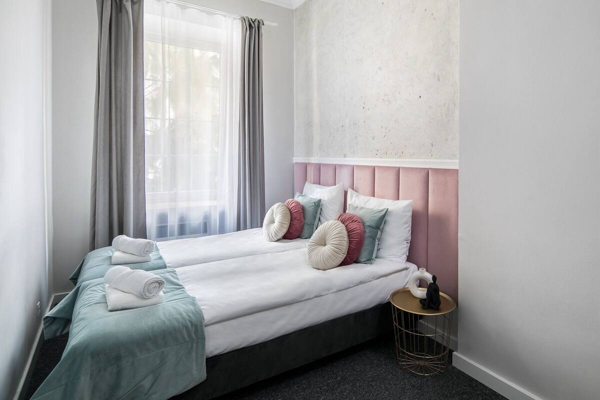 A double bed with a grey headboard, two pillows, and a bedside table with a small statue.