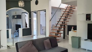 Ein modernes Wohnzimmer mit Treppe, Sofa und Fernseher.