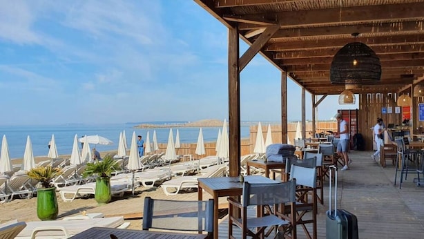 Ein Restaurant direkt am Strand mit Außenbereich, Meerblick und einer Holzterrasse.